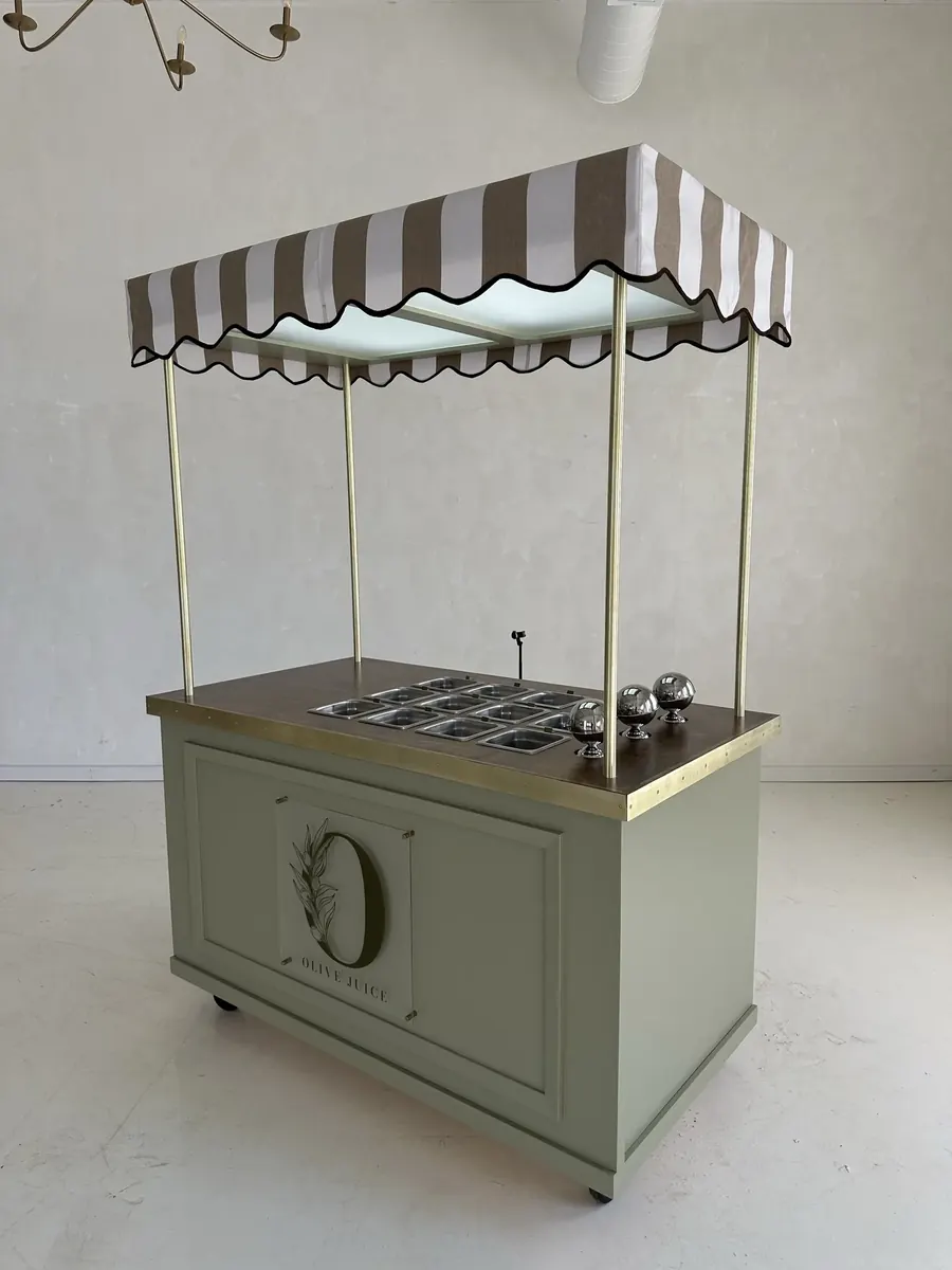 A sage green RidgeCraft awning cart with brass posts, a striped canopy and stainless wells