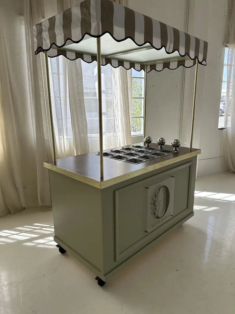 A fluted-front cart with a striped awning and brass posts