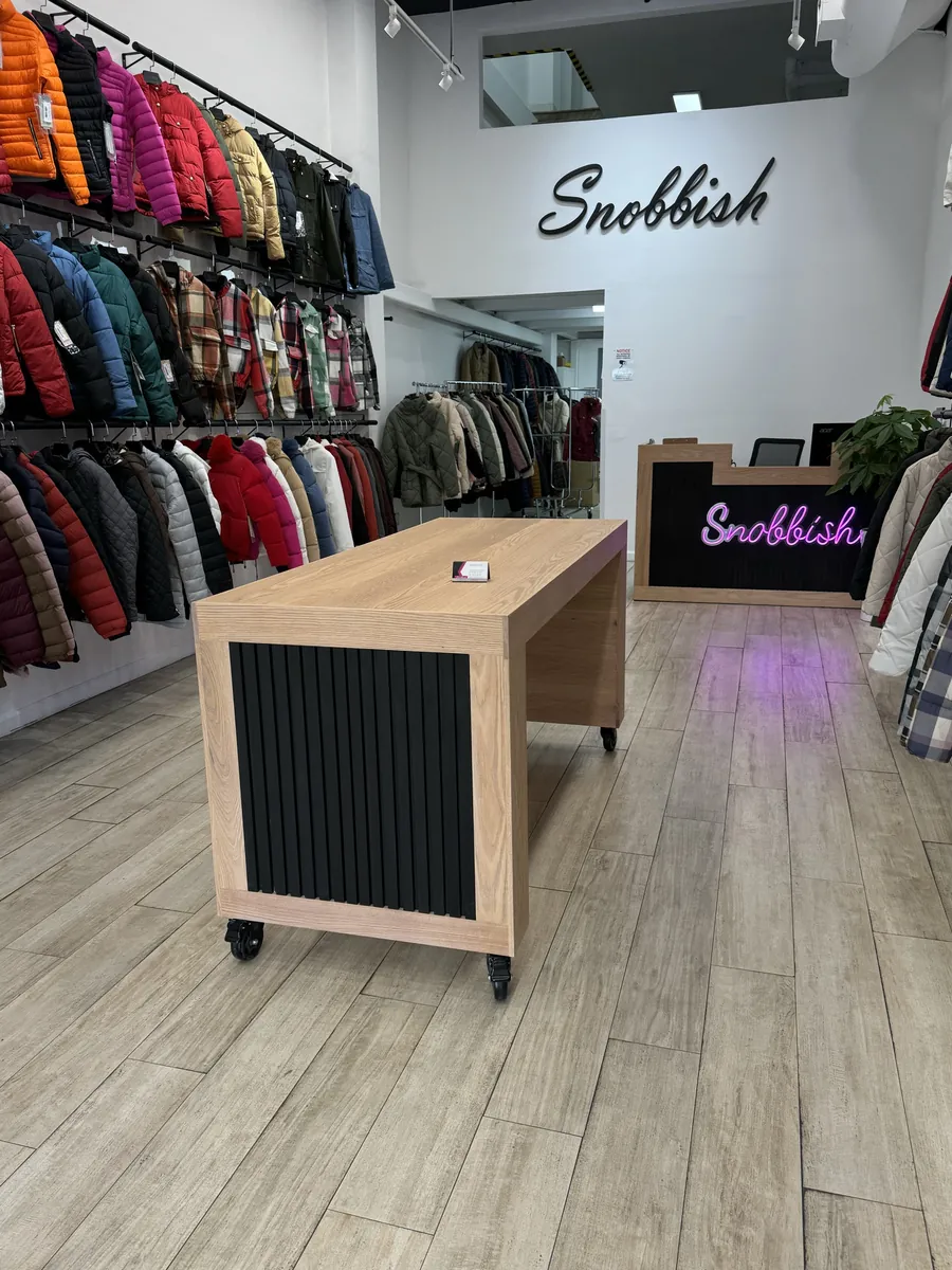 A wood-topped RidgeCraft counter on a shop floor beside a neon sign